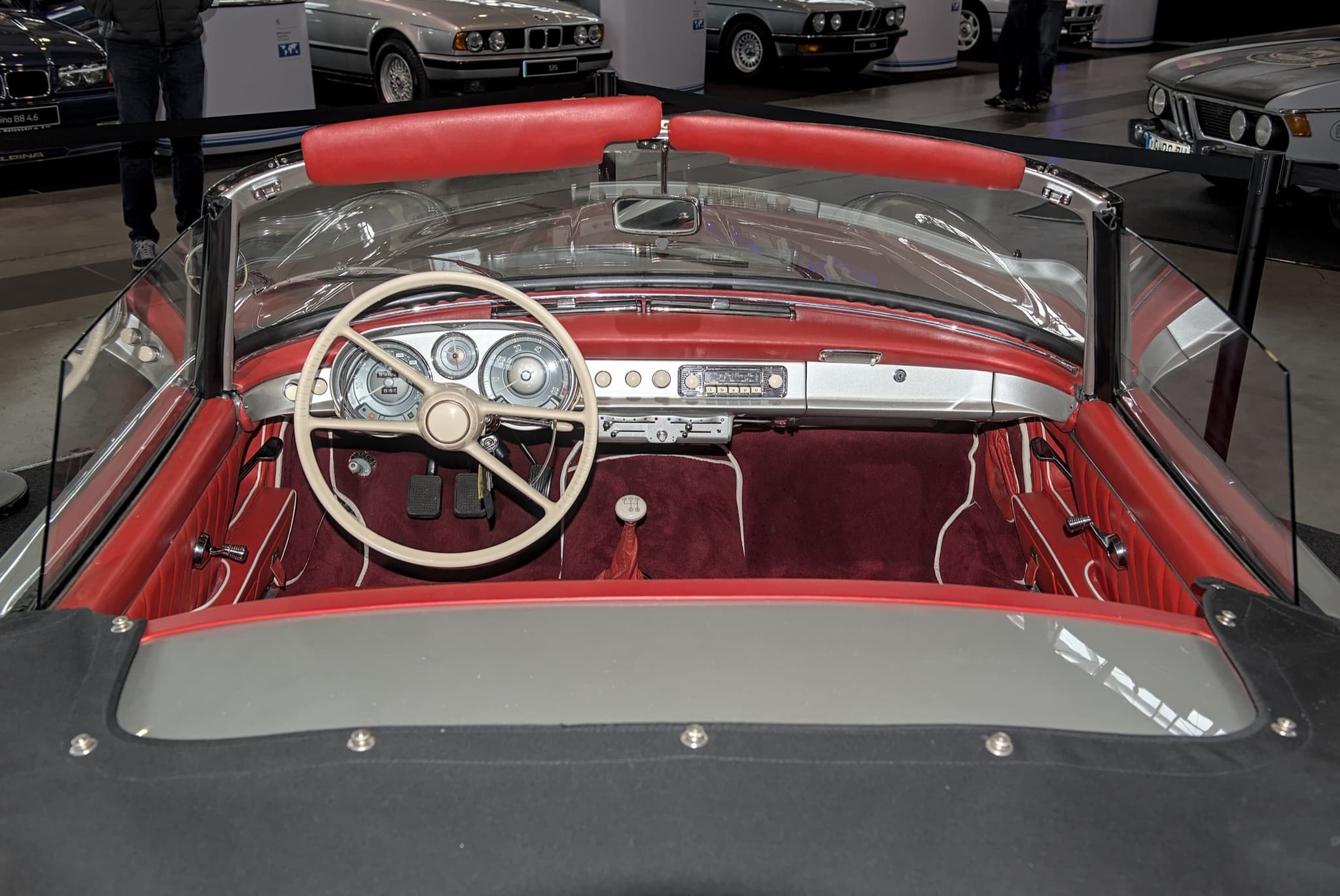 The dashboard of a BMW 507 with an ivory steering wheel, three dials, a radio with ivory buttons and a floor gear lever. Opens a larger view