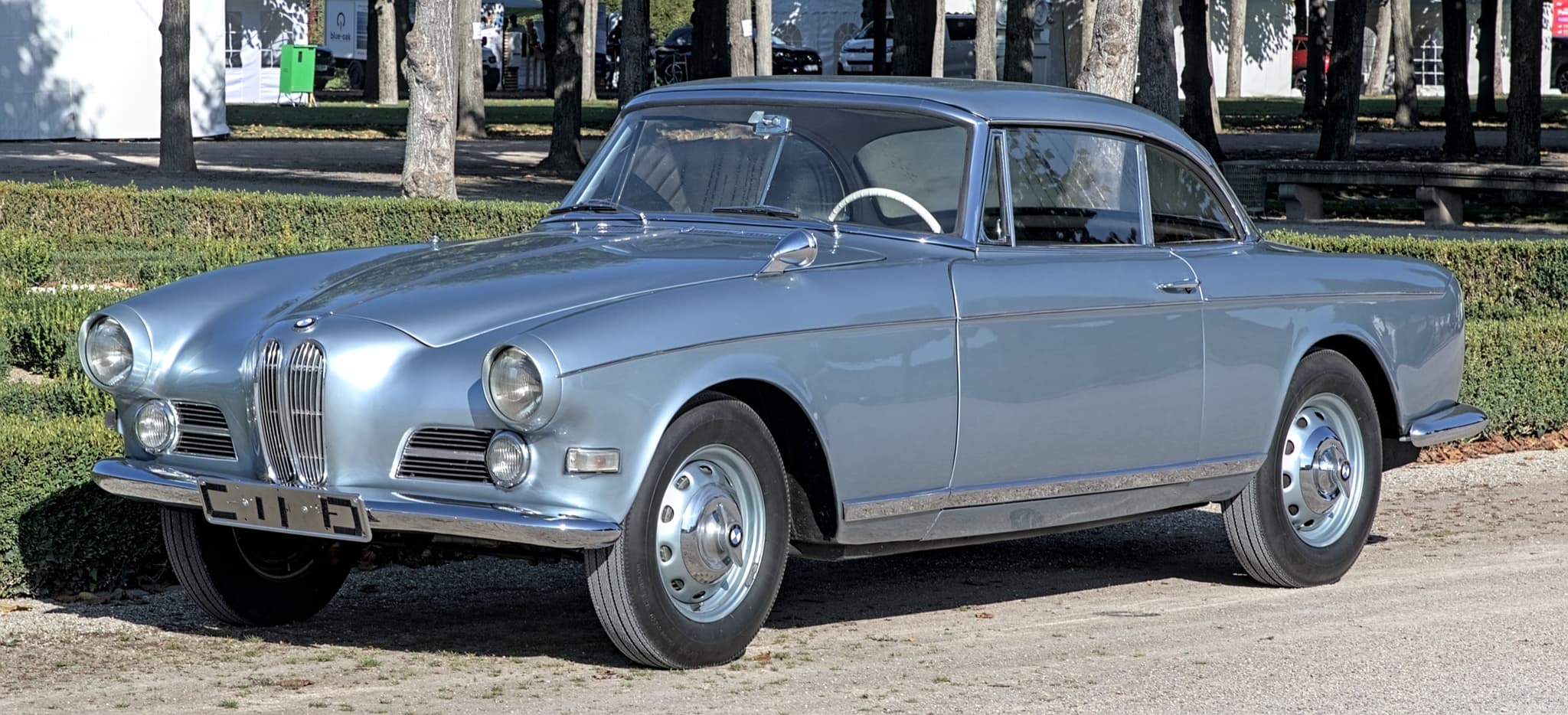 A pale blue BMW 503 coupé on gravel in a palace garden, its upright kidney grille flanked by wide side grilles.